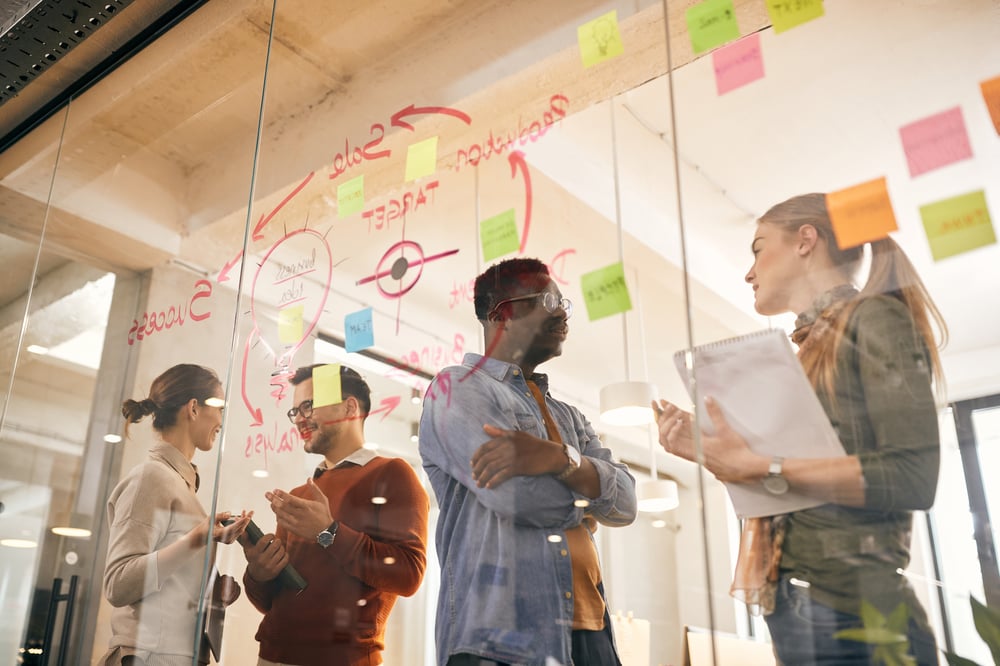 équipe travaillant ensemble devant un tableau vitré