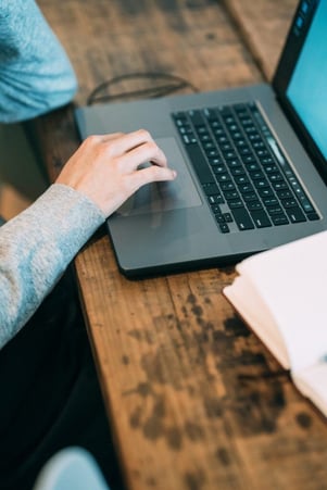 La main d'une femme bougeant les doits sur le clavier de son ordinateur portable