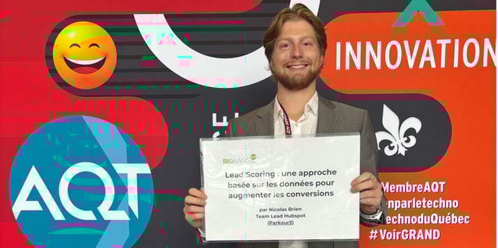 Photo de Nicolas Brien souriant devant un mur aux couleur de l'AQT