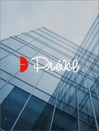 Un gratte-ciel moderne en verre s'élève vers le haut avec, au premier plan, le logo rouge et blanc de Prével.