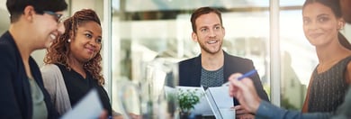 Un groupe de professionnels réunis autour d'une table, discutant de documents avec de la verdure en arrière-plan.